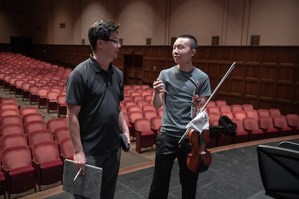 Chris Kim, Choi Family Director of Instrumental Activities, and Michael Kwan talking during rehearsal