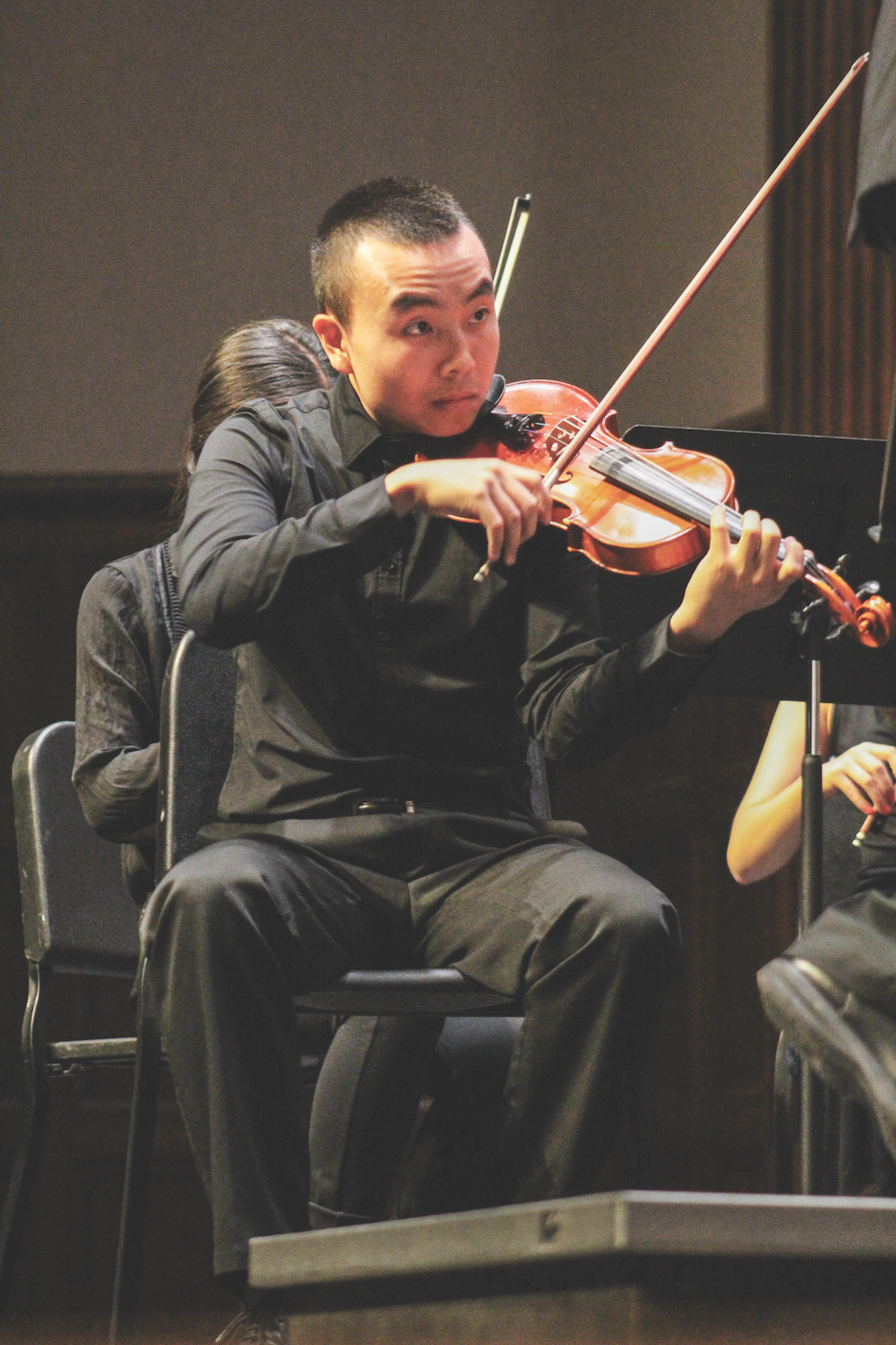 Michael Kwan playing the violin at a orchestra concert 