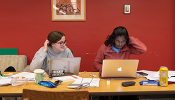 Two students study together on their laptops