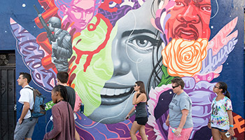 Students walk in front of a colorful street mural in Los Ang