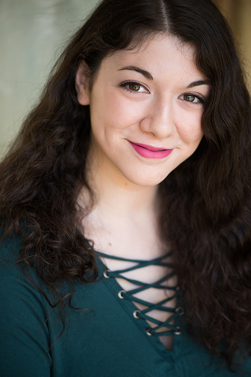 Eliana has dark curly hair and is wearing a green shirt