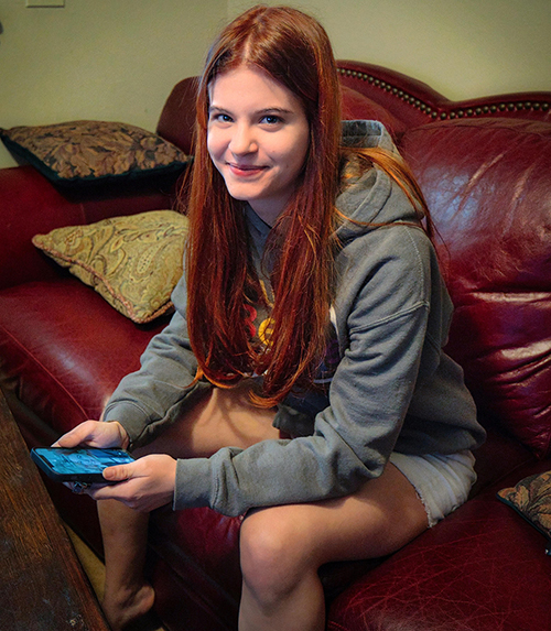 Amber is sitting on a couch, facing the camera and smiling