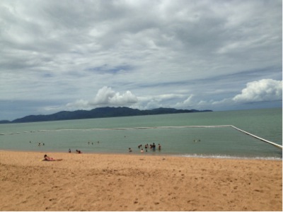 A view of a sandy beach and people swimming in the ocean