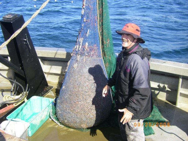 A man next to a large Trawl net full of fish.
