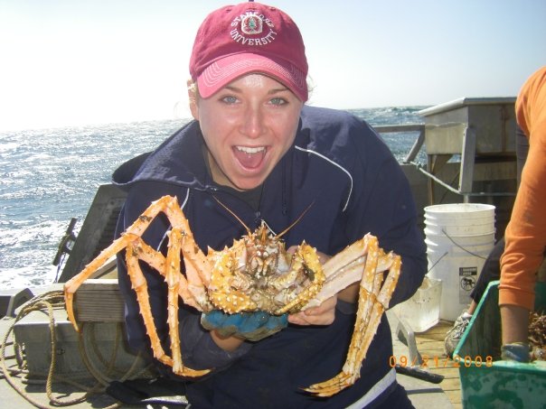 An Occidental College student holds a Trawling Crab on a boat 