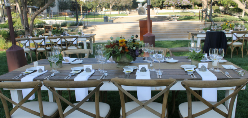 a beautifully set table with napkins, plates, silverware and a flower arrangement in the center