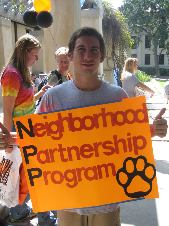 An Occidental College student holding up a Neighborhood Partnership Program sign