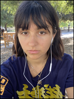 a young woman with brown hair, bangs and wearing earbuds