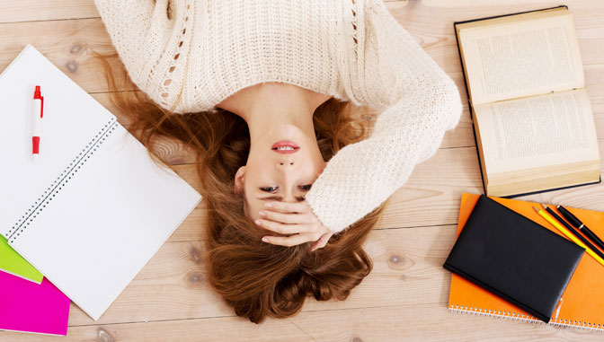 a stressed looking student in a sea of books