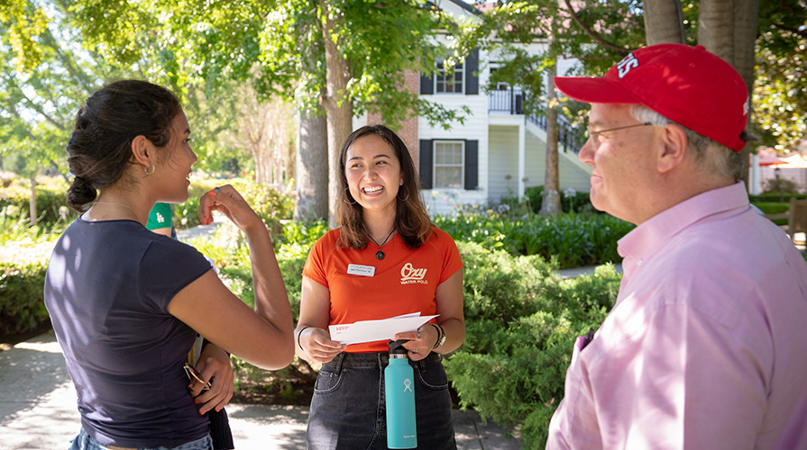 Smiling tour guide wearing orange shirt with Oxy logo, backed by Collins House