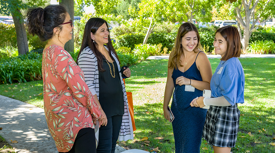 Two students smile while attending an admission event, in group with their parents