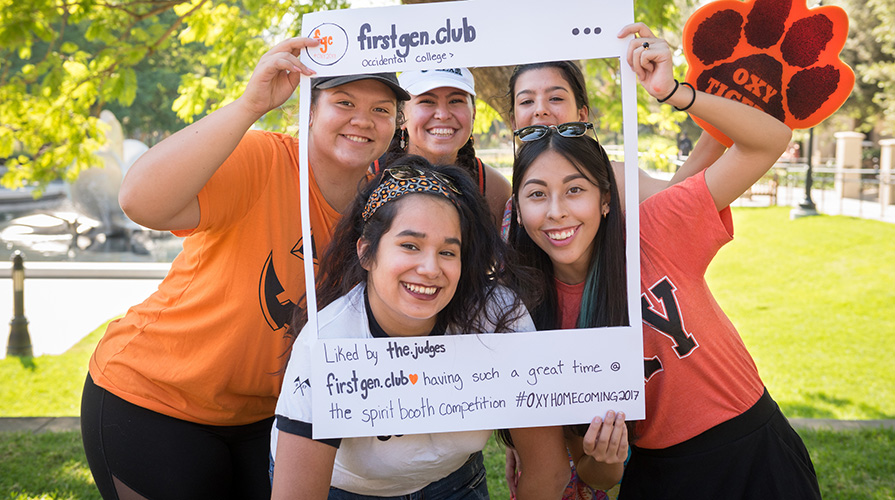 Five students pose surrounded by white poster board reminiscent of Instagram with handle @firstgen.club