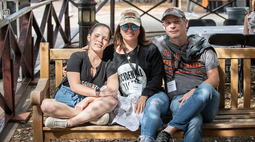 Student smiles sitting on bench with her parents, all wearing Oxy T shirts