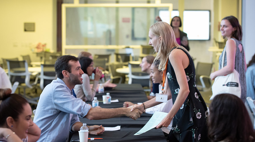 A student shakes the hand of a prospective employer for Oxy's InternLA program
