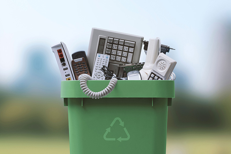 a green recycling bin full of e-waste