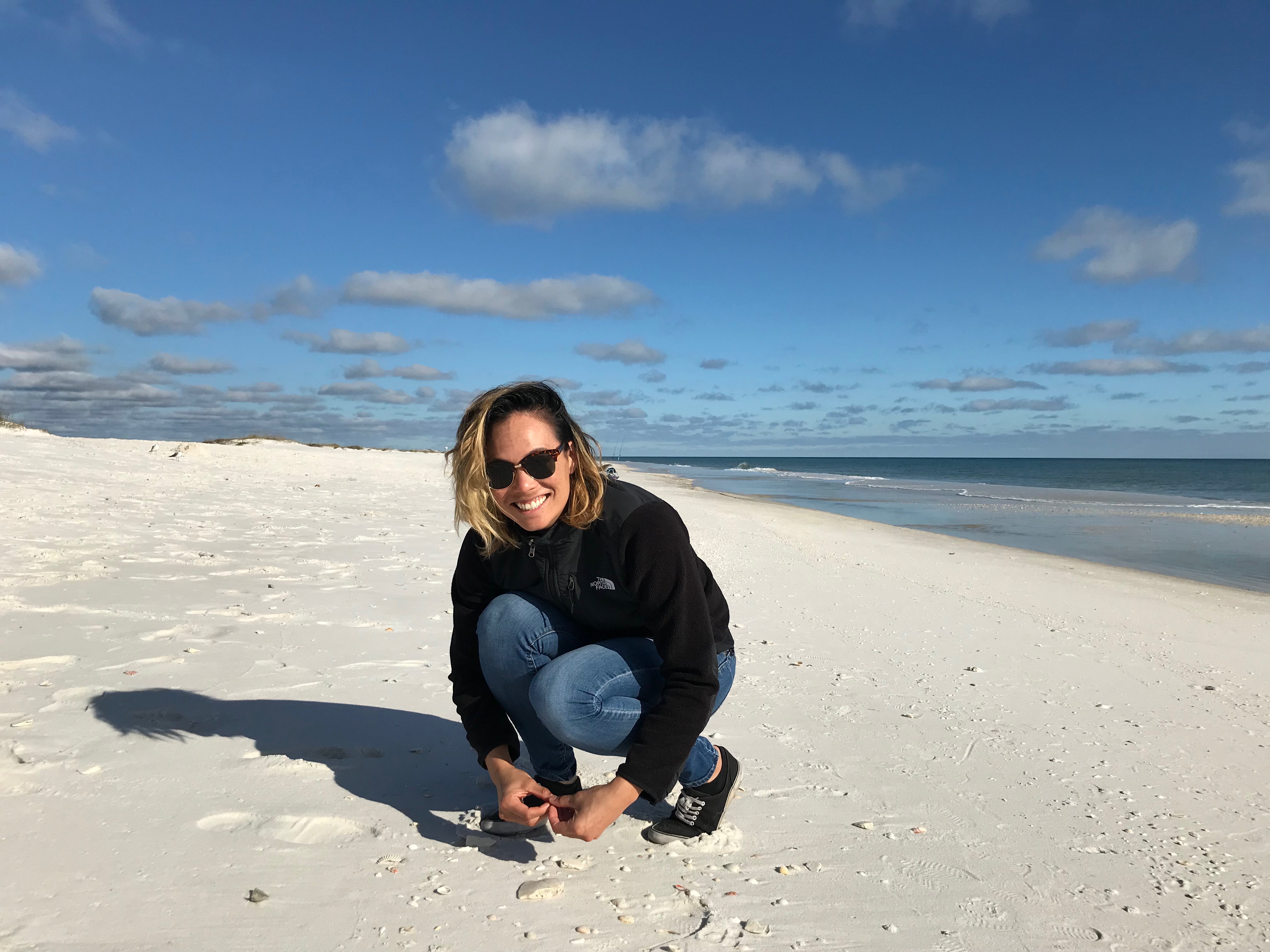 Dr. Caitlin Fong crouching on a beach