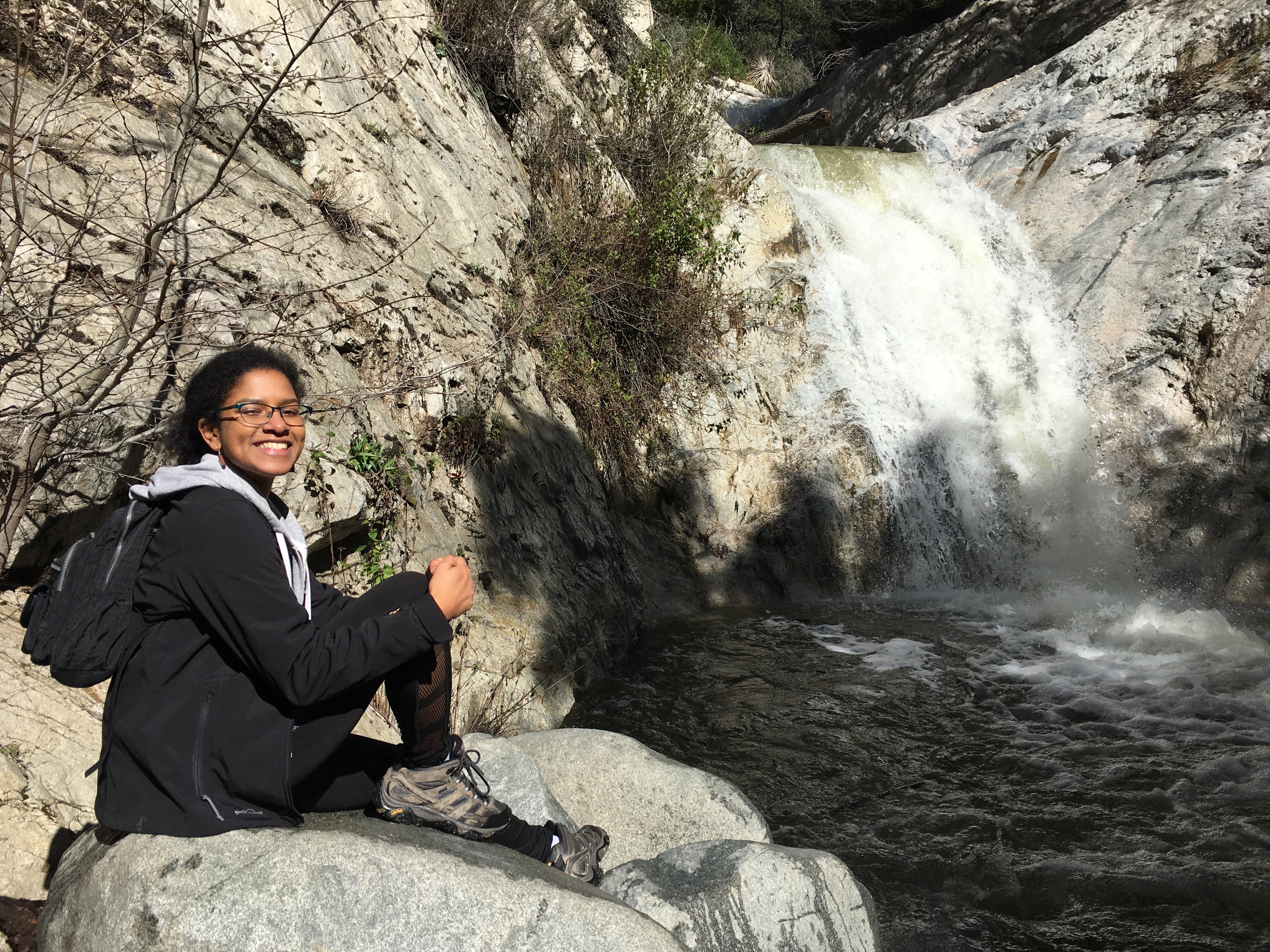 Roshni Katrak-Adefowora sitting in front of a waterfall