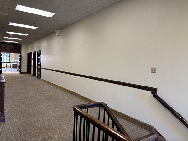 Long empty wall in a hallway with several doorways at the end