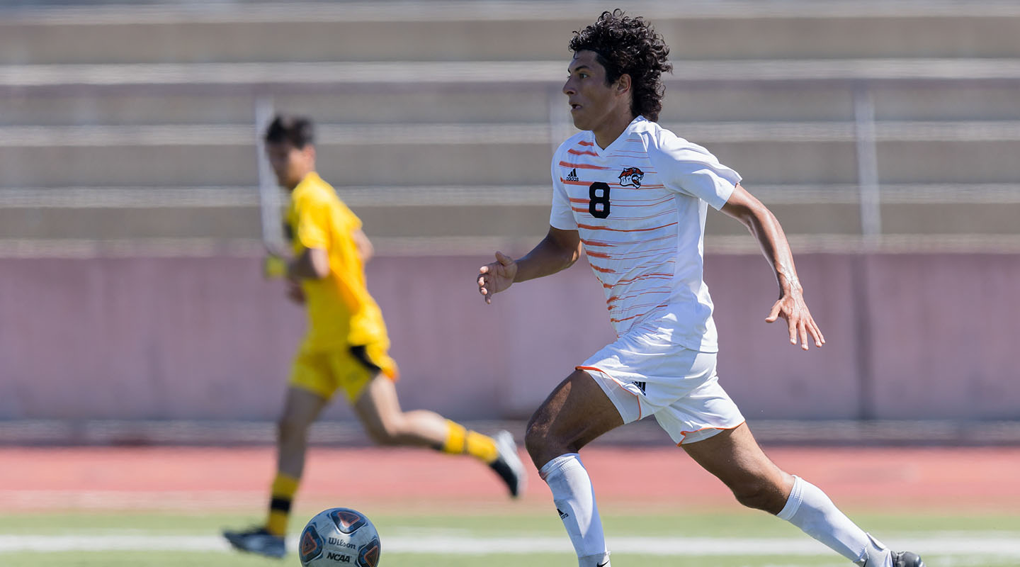 Student Tye Hernandez kicking a soccer ball on the field