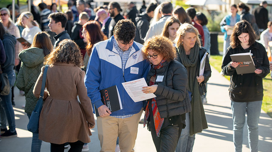 A prospective student and his mother looking at handouts, together on campus