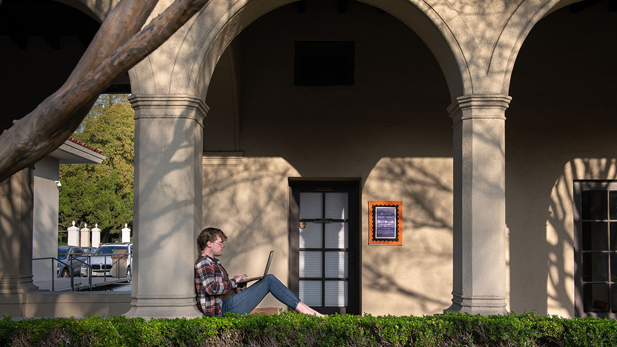 A student in Booth courtyard studying with their computer