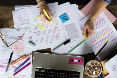 Image of a person's hands with papers, laptop, and supplies