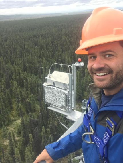 Troy Magney above trees with hard hat and equipment