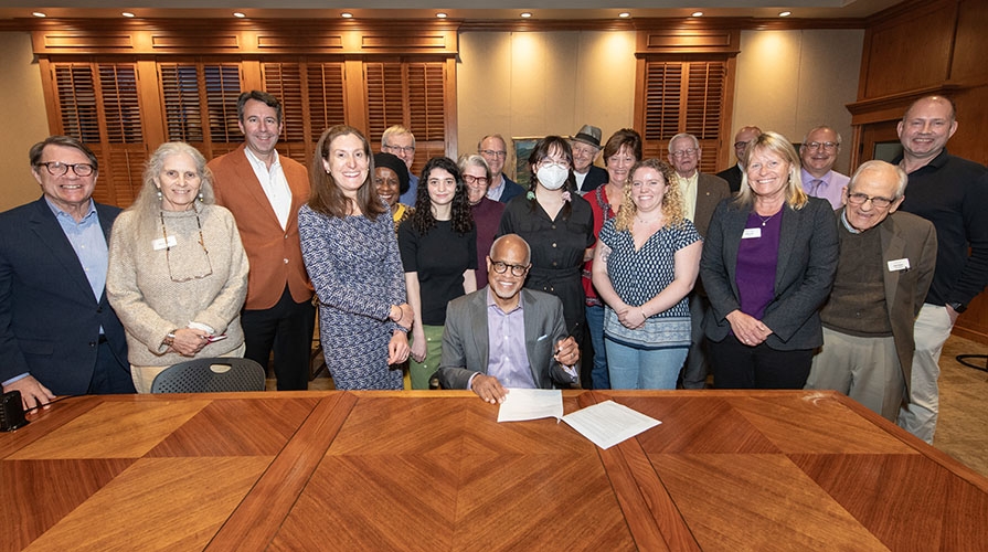 A group of Occidental College sustainability stakeholders gathered around President Elam signing a climate document