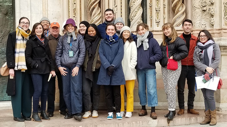 a group of Occidental students and a professor pose together on a trip to Italy in front of an old building
