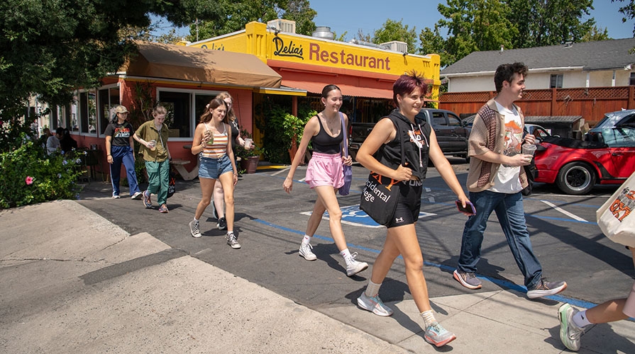 Occidental College students walking across the street in front of Delia's restaurant