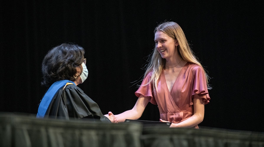 an Occidental College student receiving her membership into Phi Beta Kappa on a stage