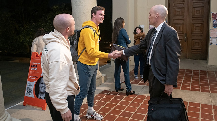 Two Oxy students shake the hand of a judge who is visiting campus to lecture