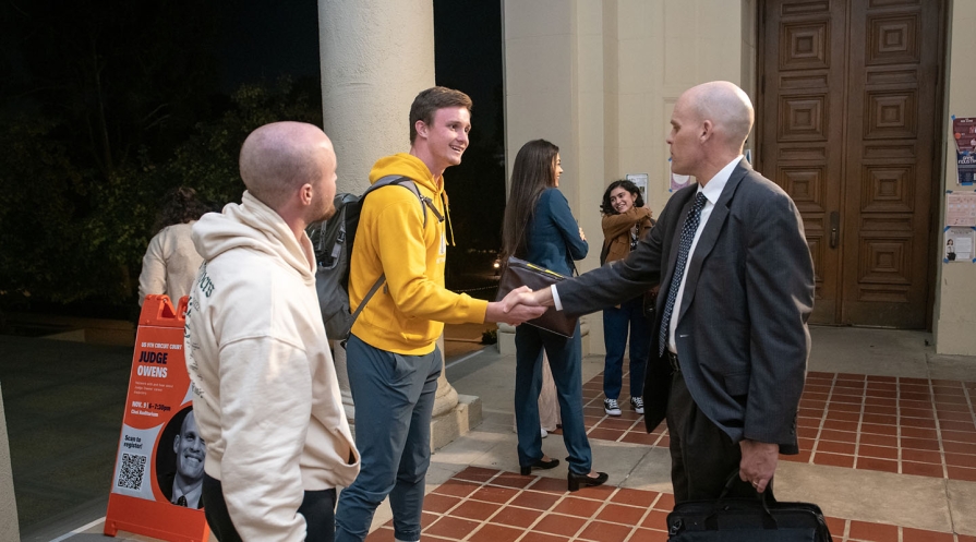 An Occidental College student shaking the hand of Judge Owens in a suit