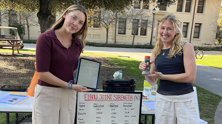 Two Occidental kinesiology students showing data collected on elbow strength