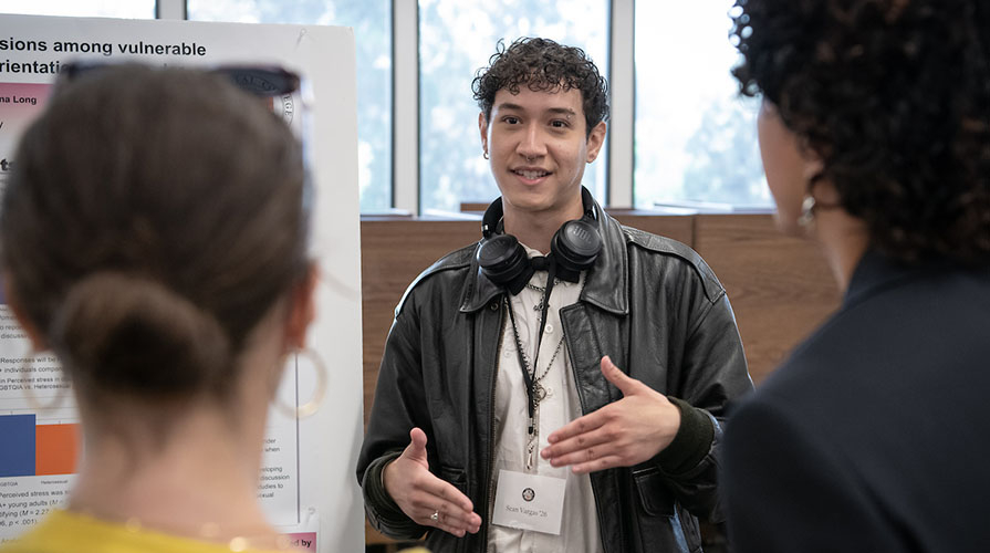Occidental College student presents his research poster to attendees at the URC conference