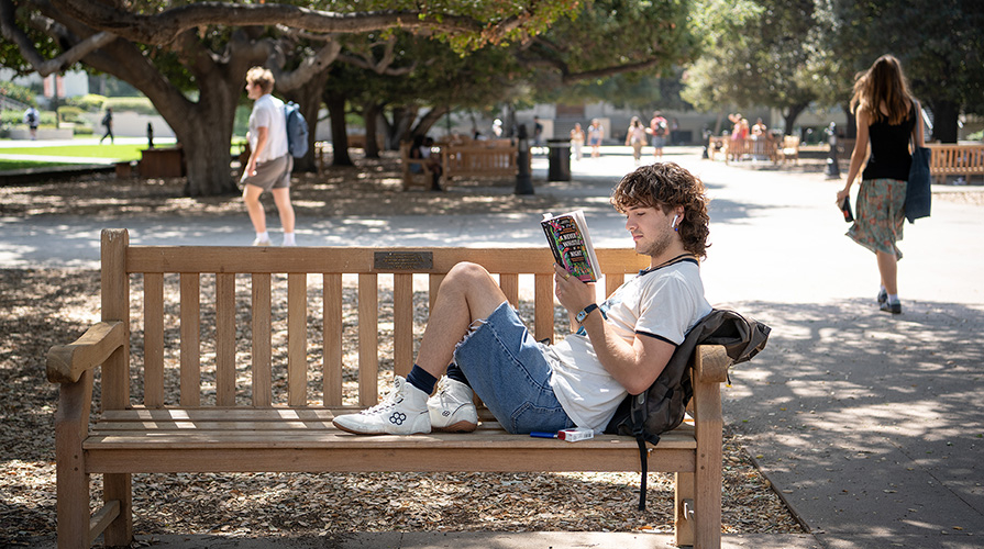 An Occidental student reads a book on the Academic Quad.