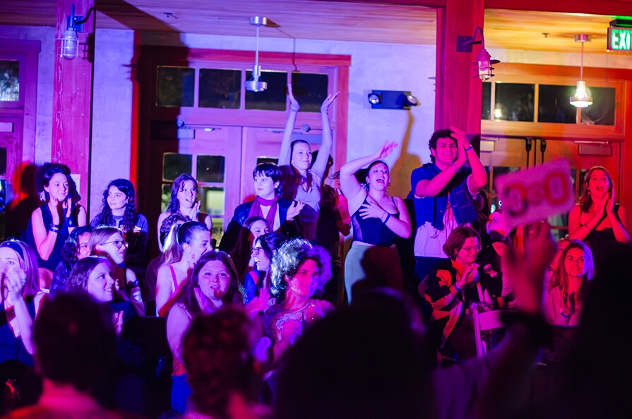 Group of student clapping in a dim room with pink light