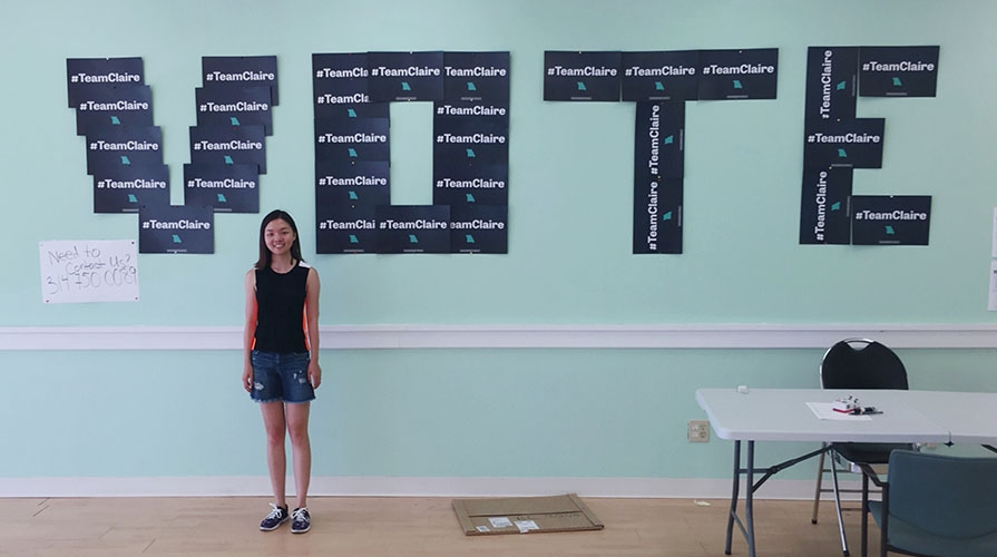 Student stands in front of wall decorated with campaign signs