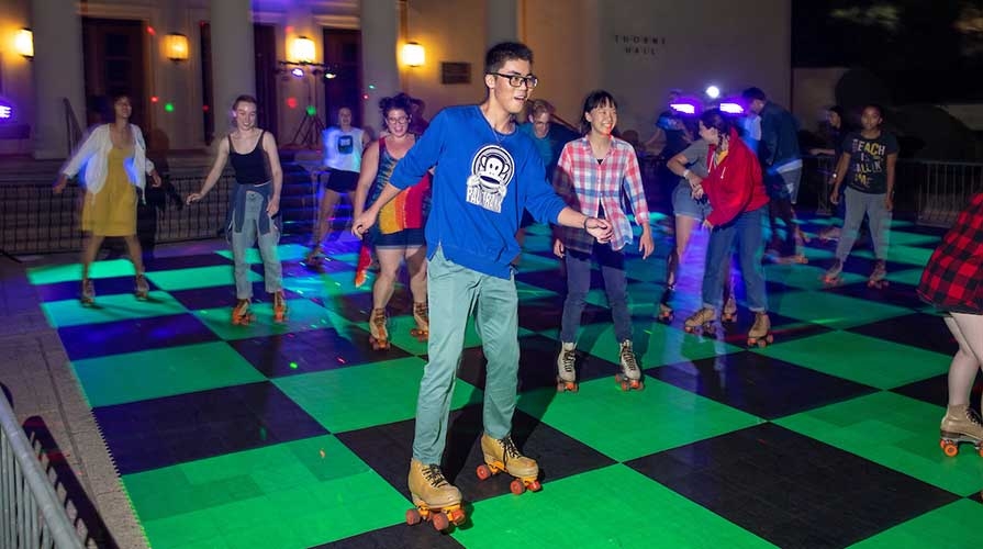 Students rollerskating on the pavement in front of Thorne Hall