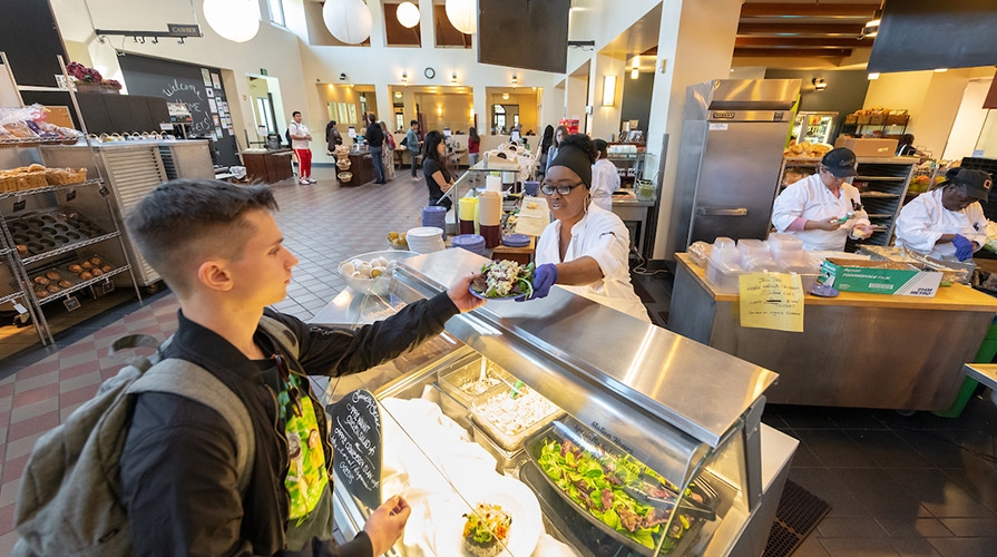 A student accepts a plate at the dining hall salad bar