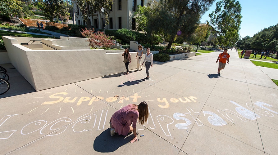 Student doing chalk drawings related to Project SAFE on campus