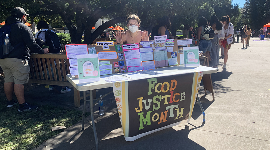 student staffing the Food Justice Month table on the quad