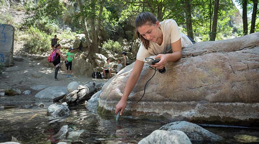 Oxy student taking water samples in a river