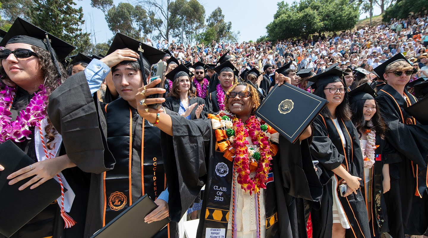 Proud graduates holding up their degrees on Commencement Day