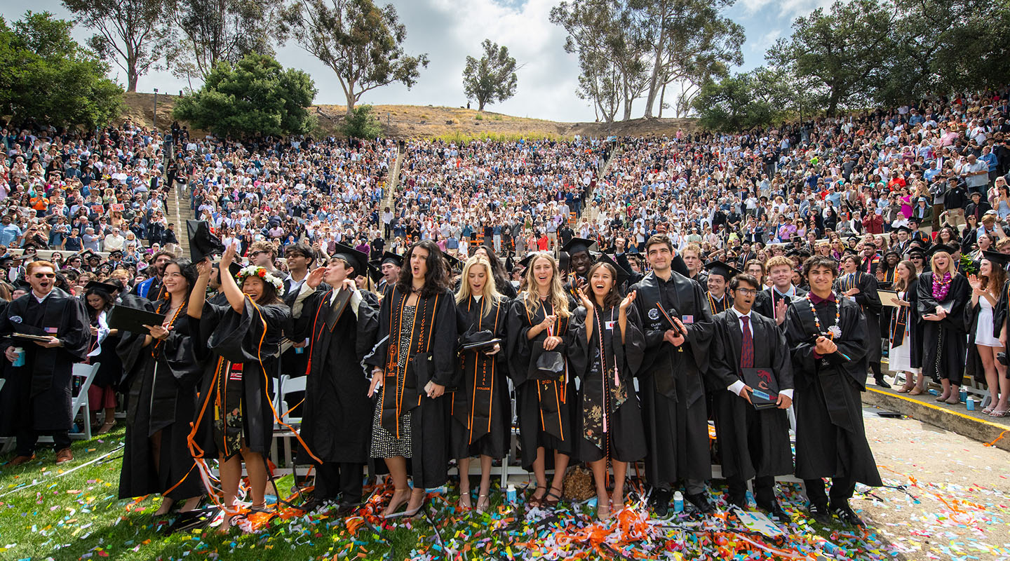 Occidental students standing in black caps and gowns in the Remsen Bird Hillside Theater, celebrating