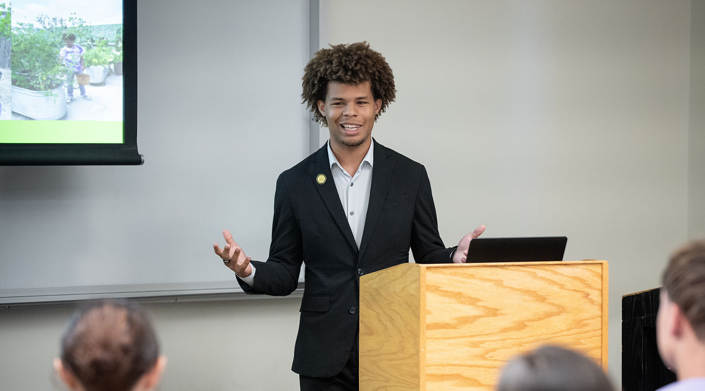 Jaymes Griggs presenting at a lectern at the Summer Research Program conference on the Occidental campus.