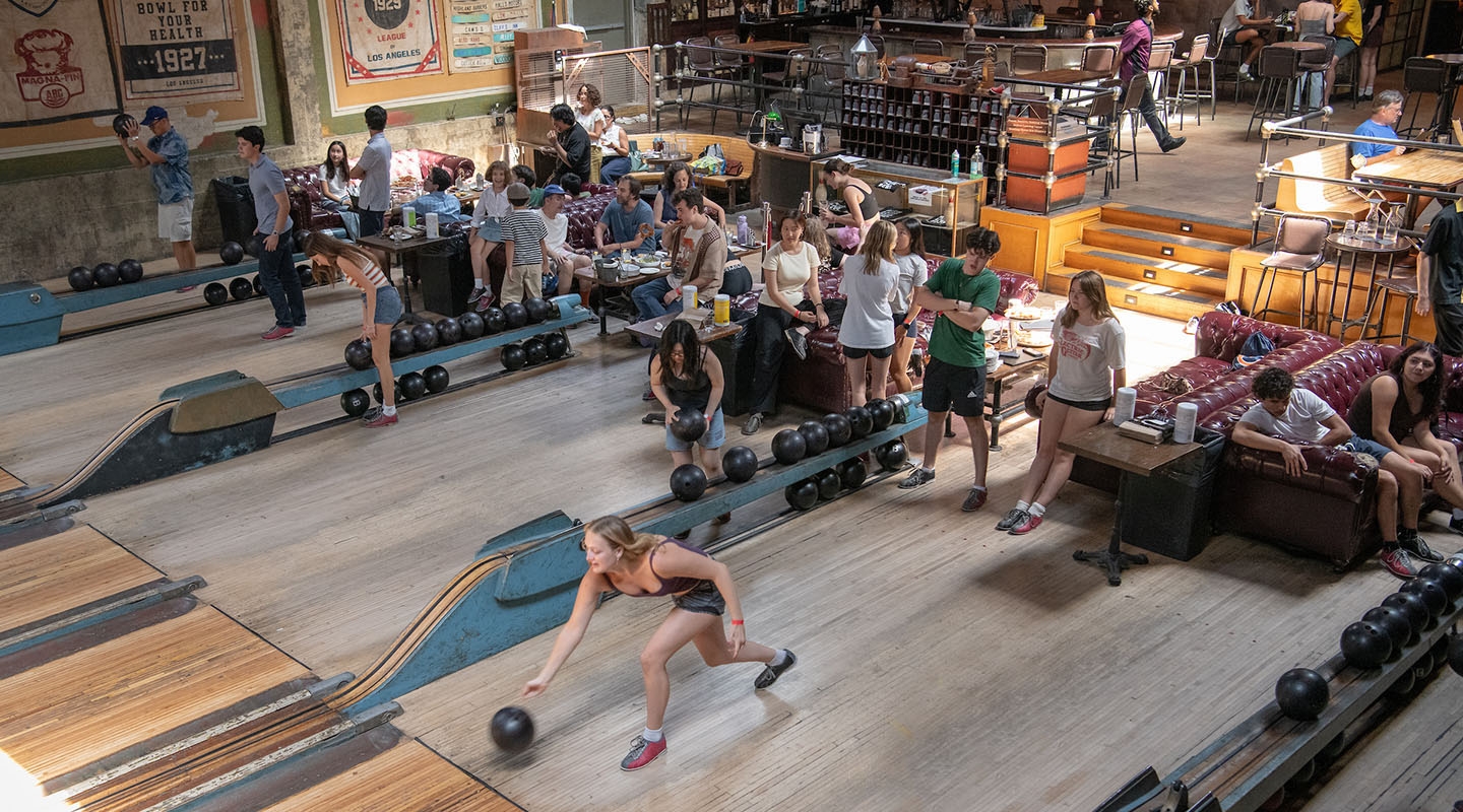 A large group of students bowling at a steampunk-themed bowling alley