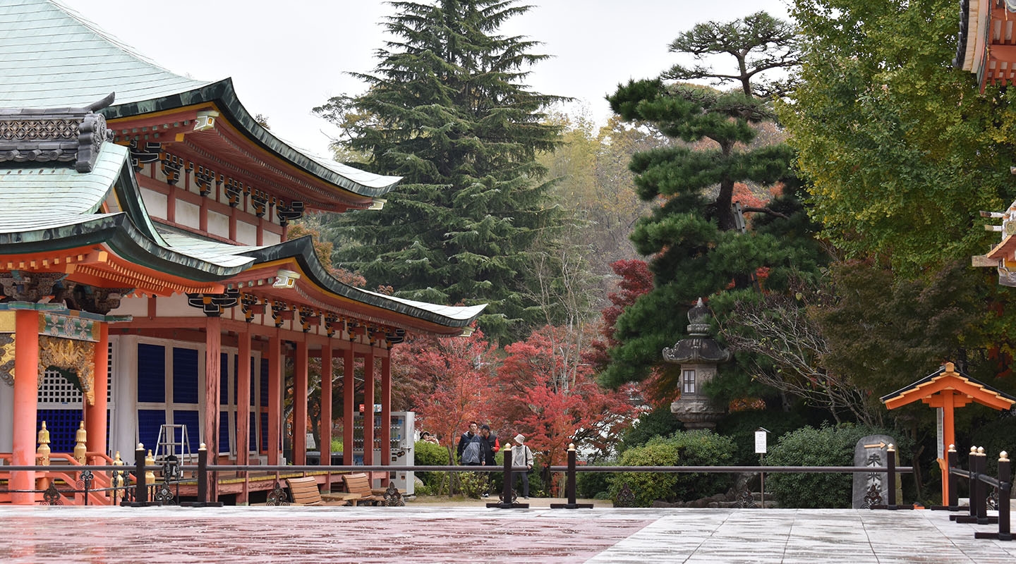 A view of the red Hiroshima temple with pine trees in the background
