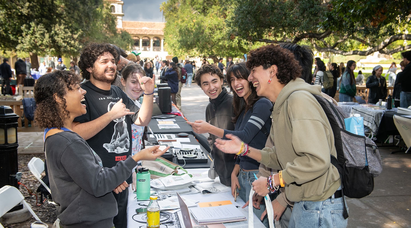 oxy students at a table at the involvement fair on the quad smiling and laughing