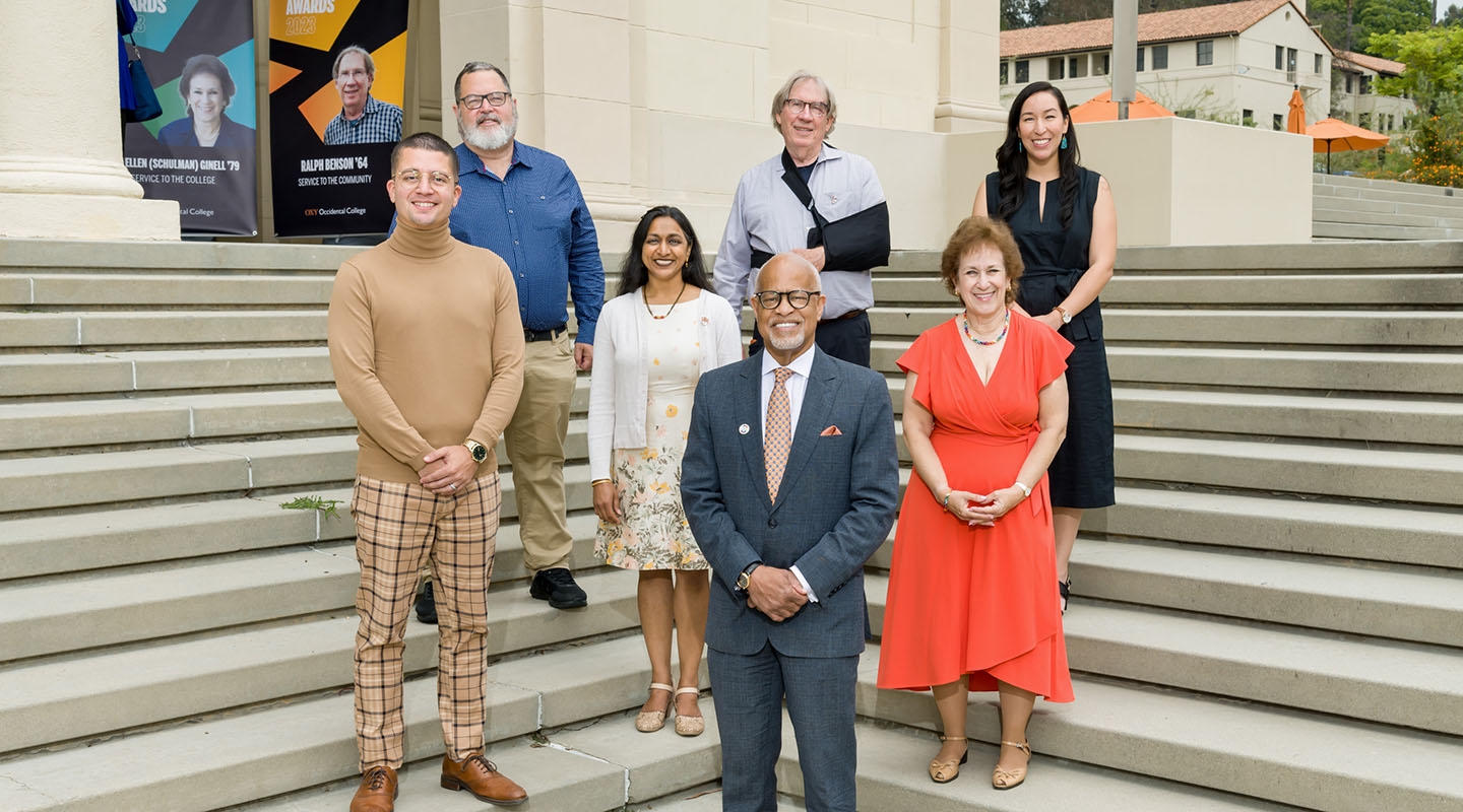 A group of alumni and President Elam stand in formation on some steps